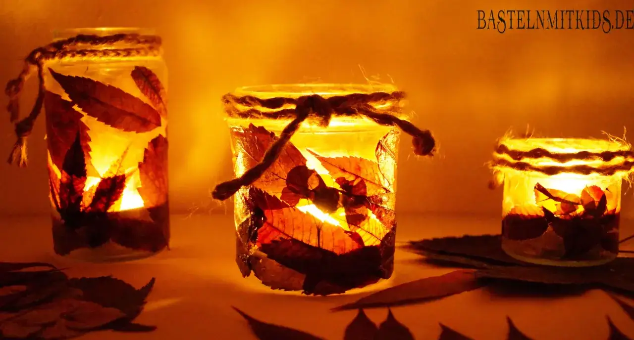 Drei leuchtende Windlichter, gebastelt mit Papier und Herbstblättern, strahlen warmes Licht aus. Ein schönes Bastelprojekt für Kinder.