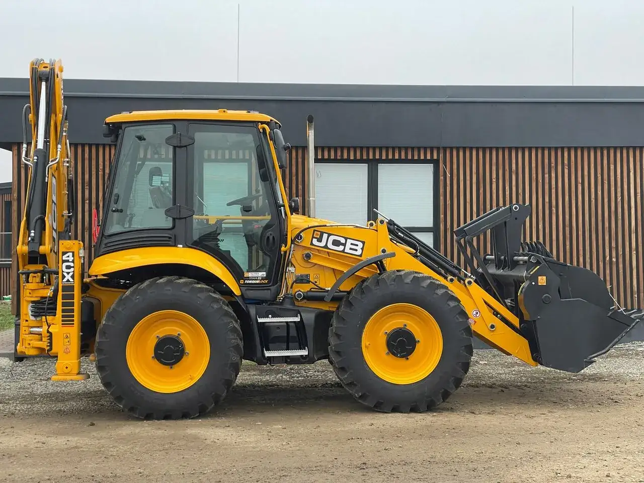 Nowa koparko ładowarka JCB 4CX lśni żółcią, gotowa do pracy.