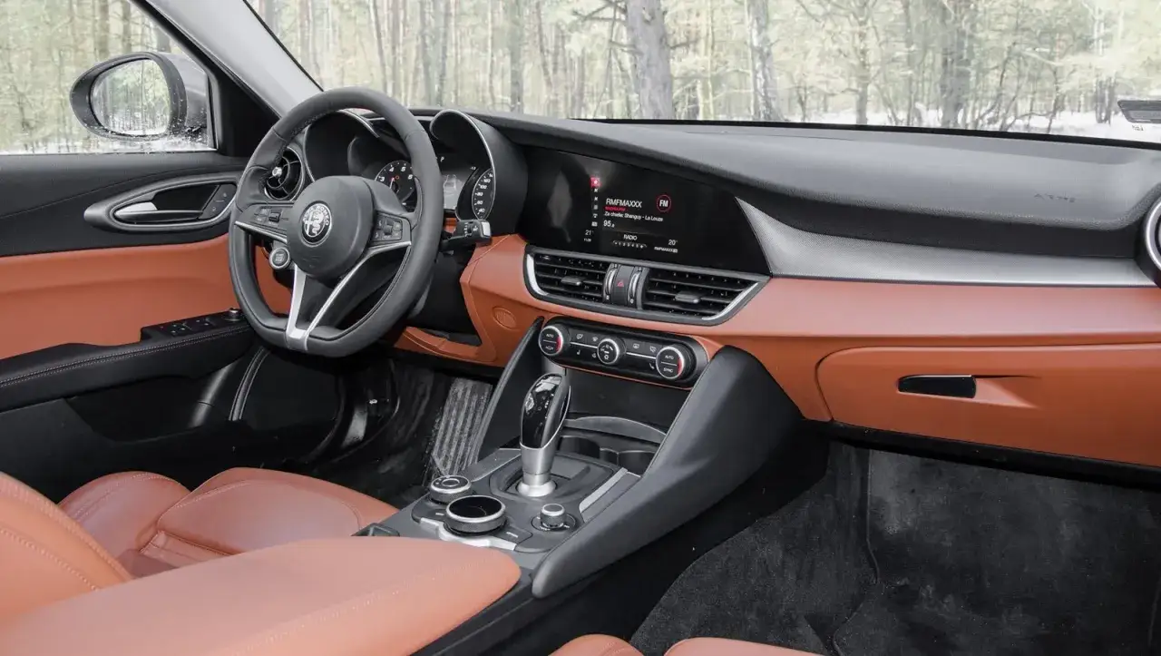 Wnętrze Alfa Romeo Giulia Veloce z brązową skórzaną tapicerką i nowoczesnym panelem multimedialnym.