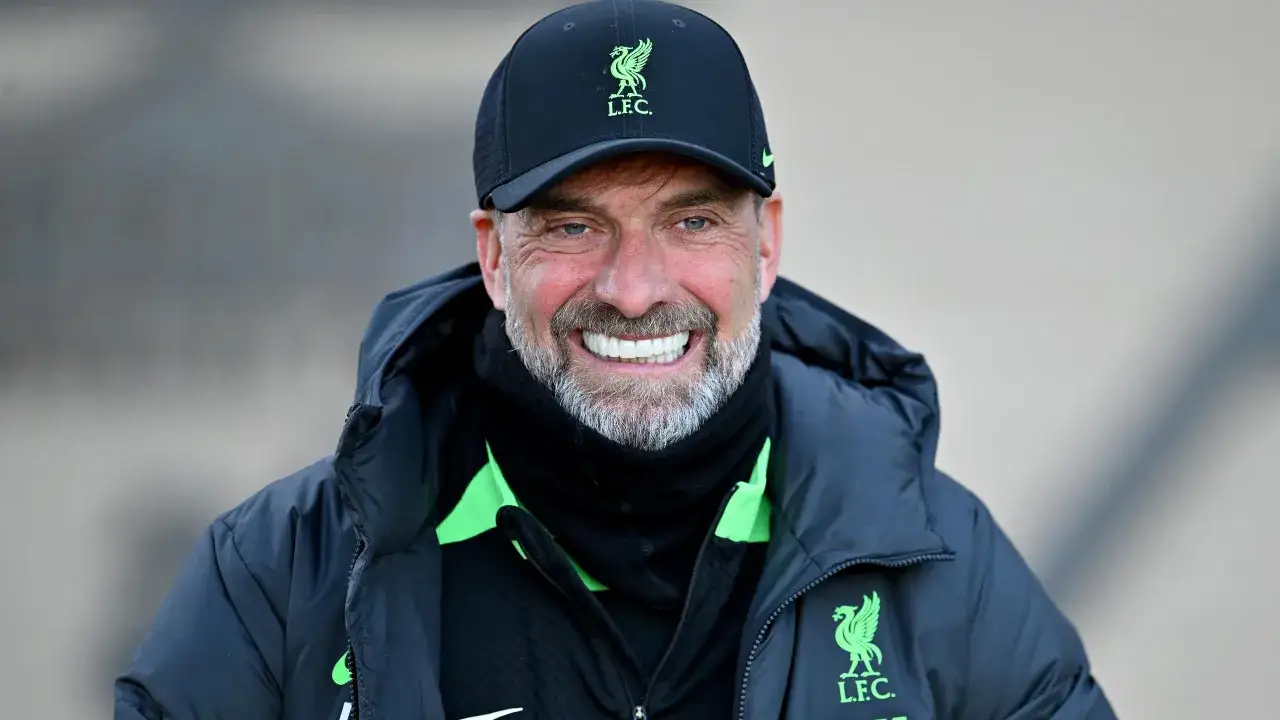 Trainer Klopp lächelt breit in die Kamera, trägt eine schwarze Kappe mit dem LFC-Logo und eine dunkle Jacke.