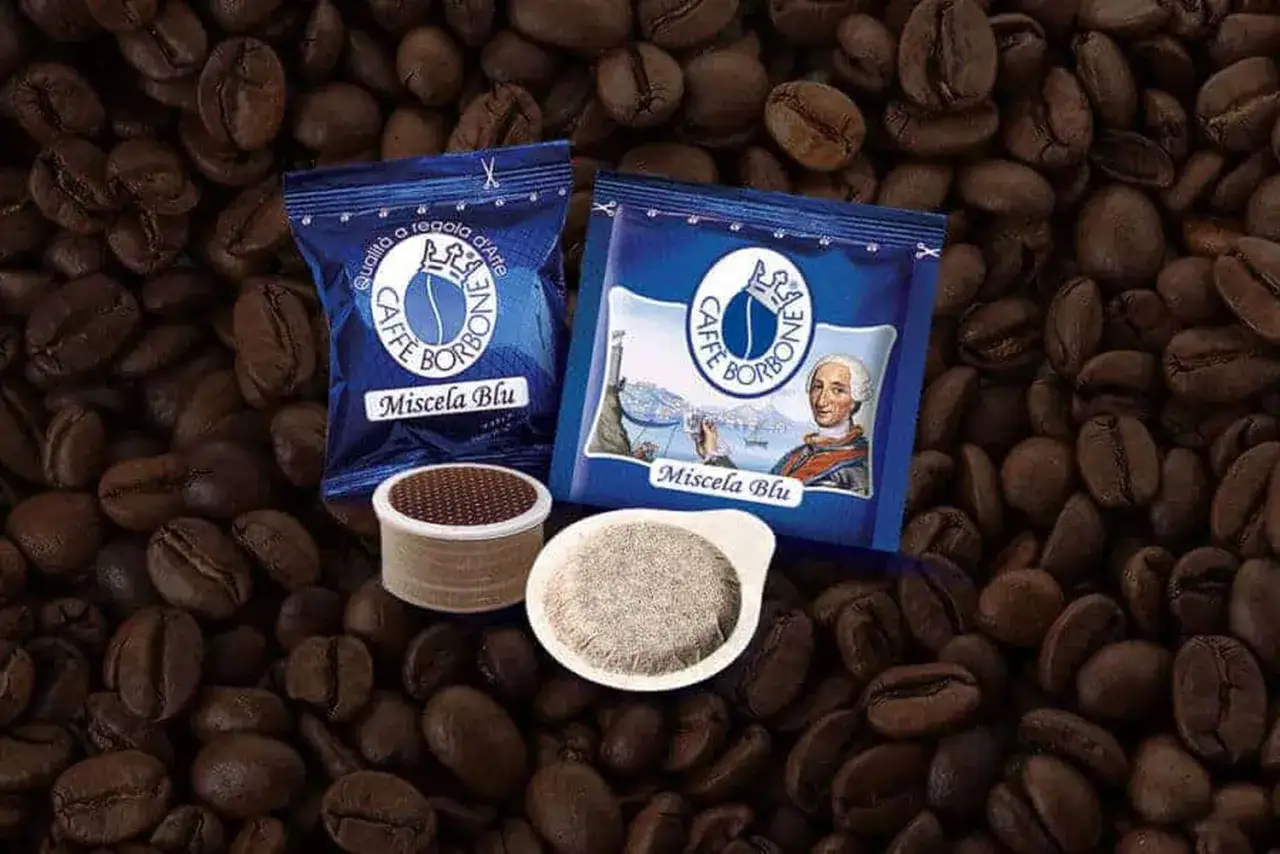 Due confezioni di caffè Borbone Miscela Blu e due cialde o capsule, su uno sfondo di chicchi di caffè tostati.
