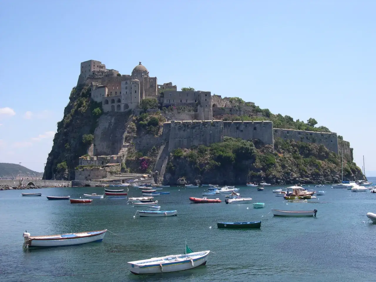 Il castello domina la scogliera, mentre piccole barche solcano il mare. Sembra il rifugio del corsaro dell'isola verde.