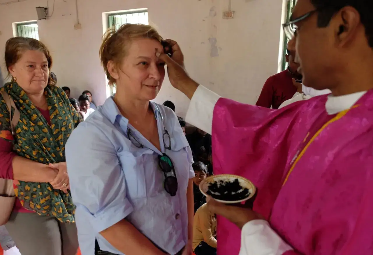A priest applies ashes to a woman's forehead, marking Ash Wednesday. This solemn ritual reminds us of our mortality and the scripture,