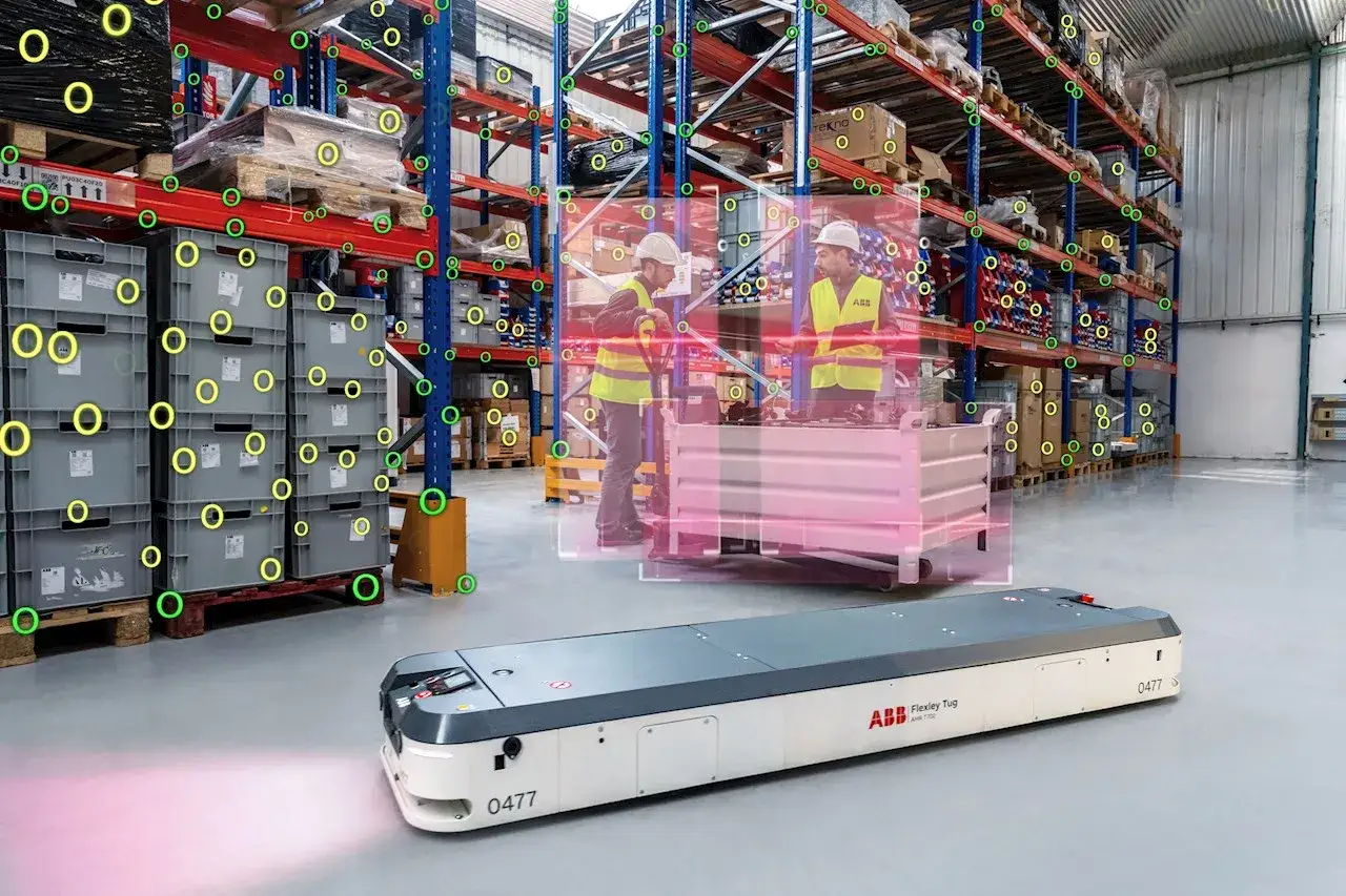 Autonomiczny robot transportowy w magazynie, przykład innowacji w logistyce. Pracownicy w kamizelkach obserwują jego pracę.