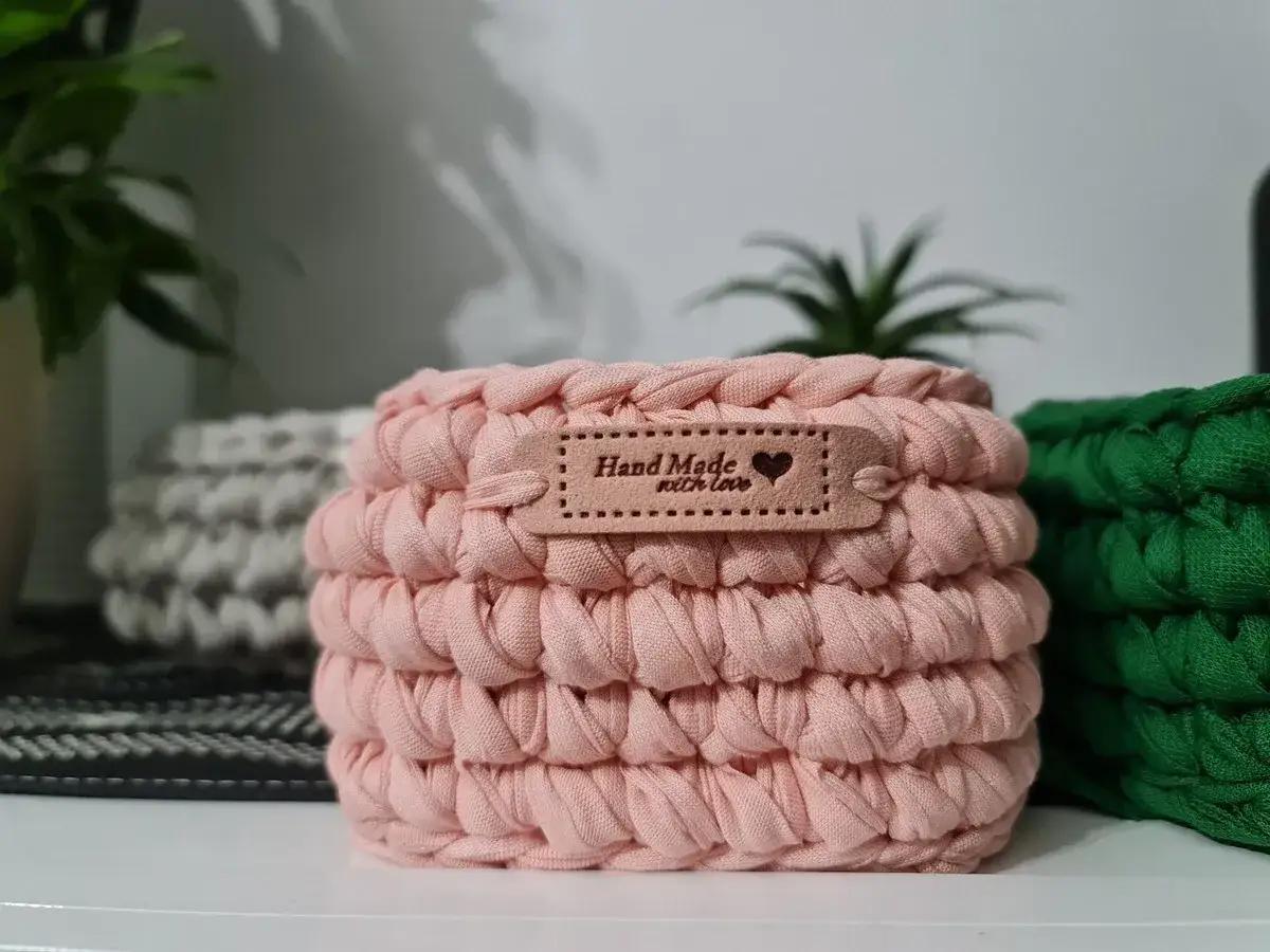Delicati cestini uncinetto rosa, grigi e verdi, con etichetta 