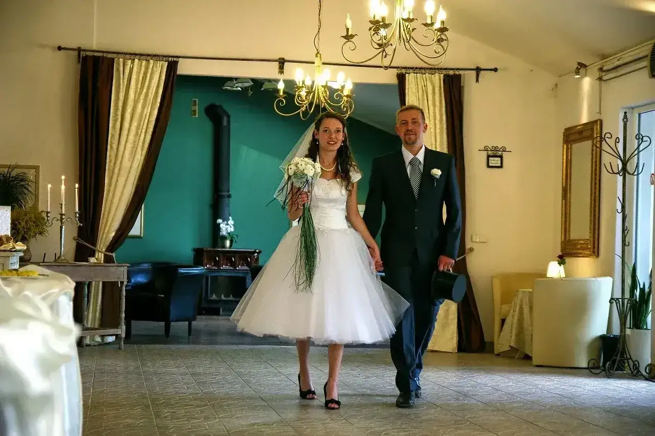 Para młoda idzie do ołtarza. Suknia panny młodej przypomina styl wesele lata 80.