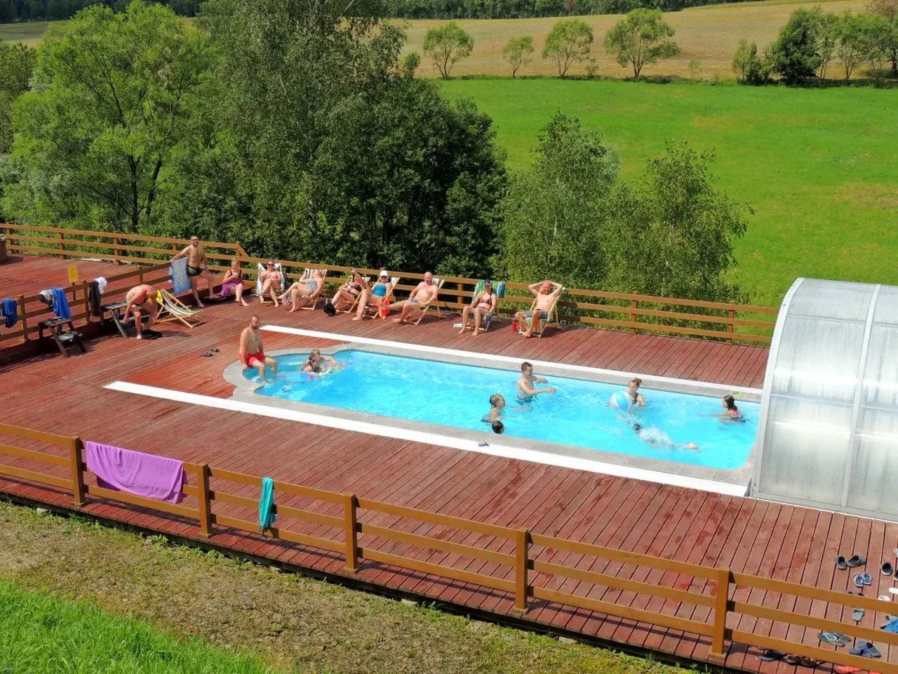 Relaks przy basenie w hotelu w Bieszczadach. Ludzie opalają się na leżakach i pływają w basenie.