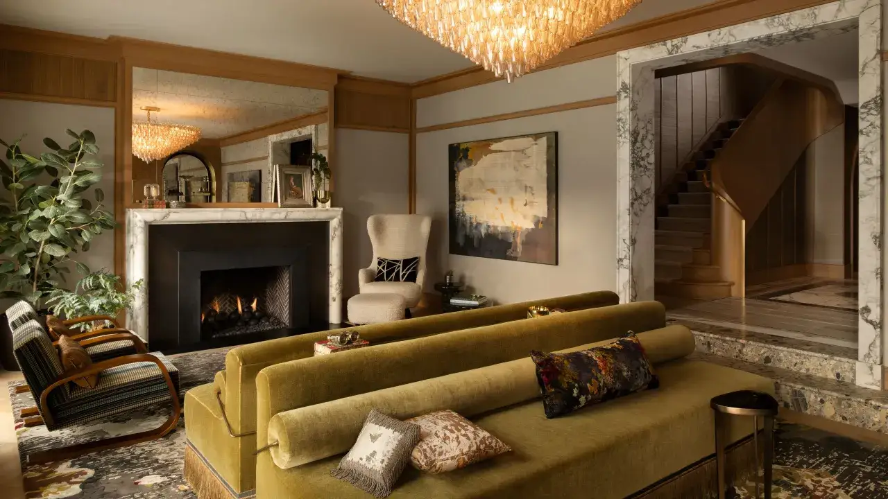 A luxurious living room with a fireplace, plush velvet sofas, and a grand staircase, showcasing the opulent style of art deco.