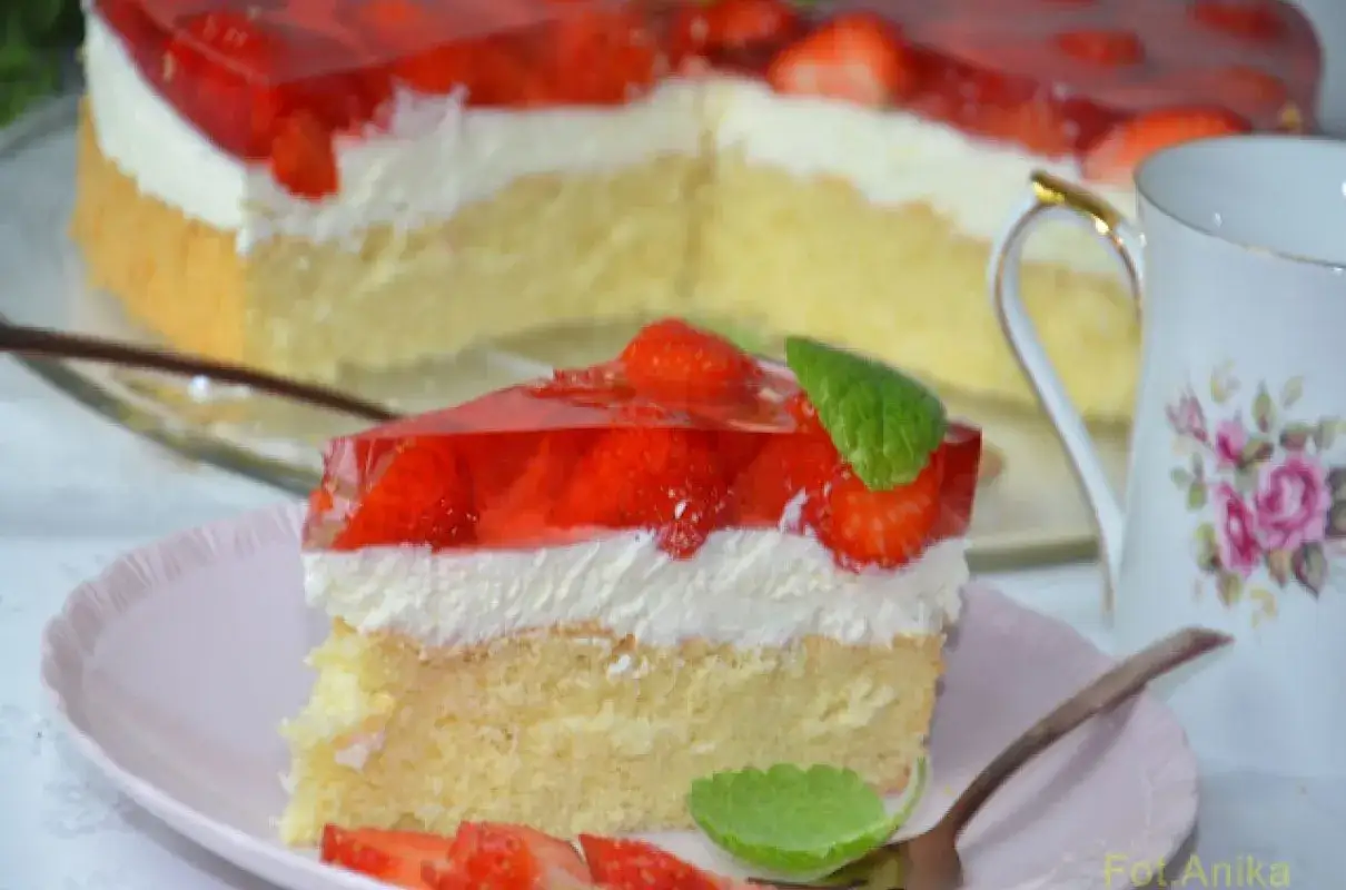 Pyszny biszkopt przekładany mascarpone, z warstwą bitej śmietany i galaretką z truskawkami. Idealny deser.