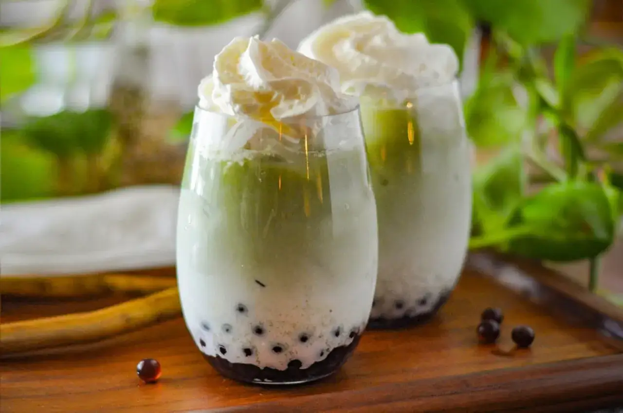 Dwa szklanki zielonej herbaty z mlekiem i pianką, z kuleczkami tapioki na dnie. Idealne, gdy zastanawiasz się, jak zrobić bubble tea.