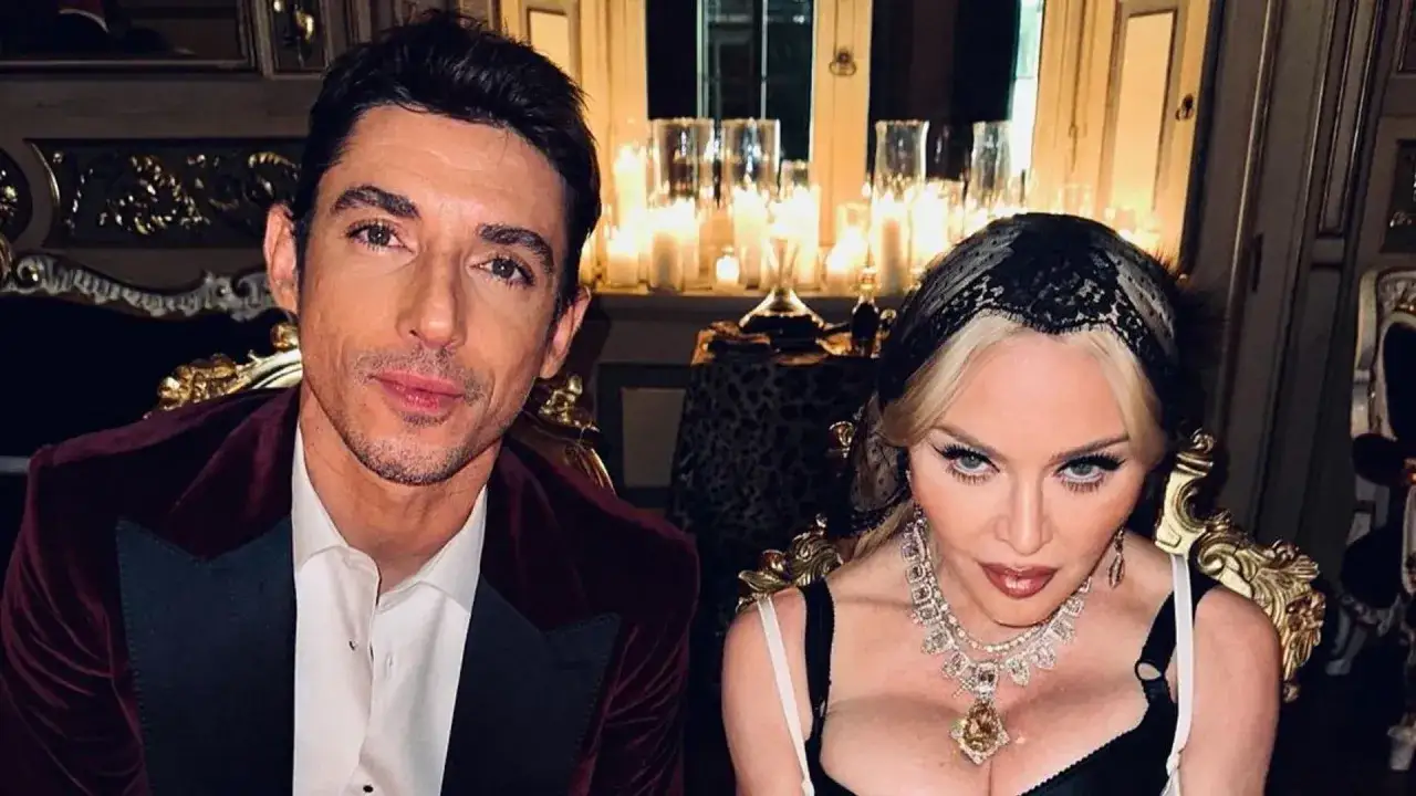 Madonna y su pareja posan elegantemente en un salón con velas encendidas.