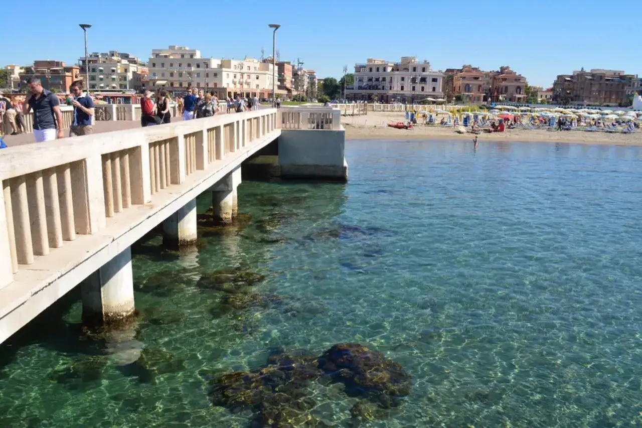 Passeggiata sul molo con vista sulla spiaggia e sul mare cristallino. A Roma c'è il mare, un'oasi di pace.