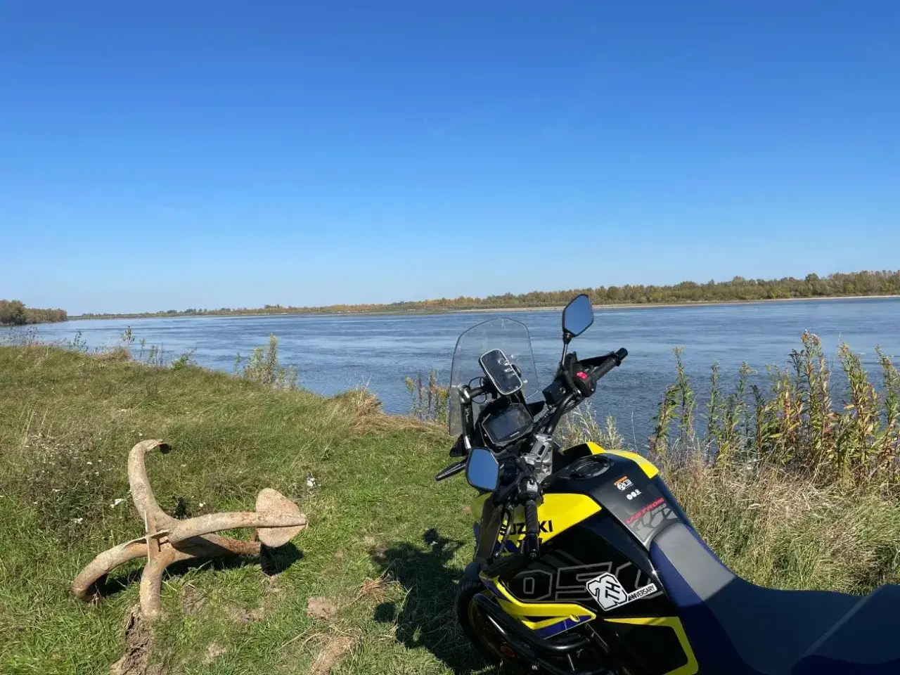 Motocykl Suzuki czeka na dalszą podróż po malowniczych trasach motocyklowych mazowieckich, nad szeroką rzeką.