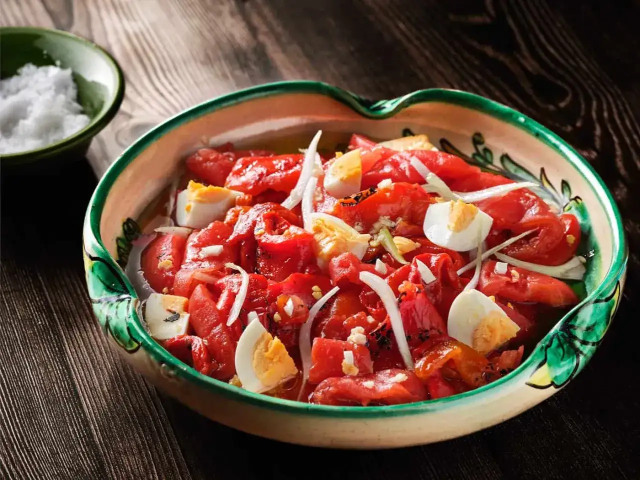 Zorongollo extreme&ntilde;o, una ensalada de pimientos asados, cebolla y huevo duro, servida en una cazuela de barro.
