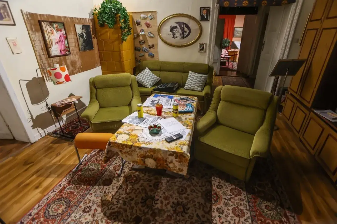 Wnętrze salonu z lat 70. w muzeum Kiepskich. Zielone fotele, kanapa, stolik z gazetami i pamiątkami.