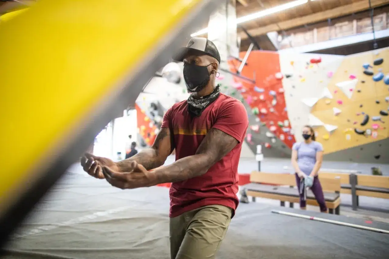 Mann in rotem Shirt, Khaki-Hose und Maske, bereit zum Bouldern. So was zieht man zum Bouldern an: bequeme Kleidung für Bewegung.