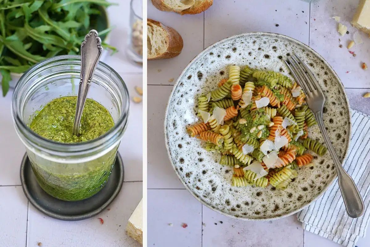 Frisches Rucola Pesto in einem Glas, daneben eine bunte Pasta mit Pesto, Pinienkernen und Parmesan.