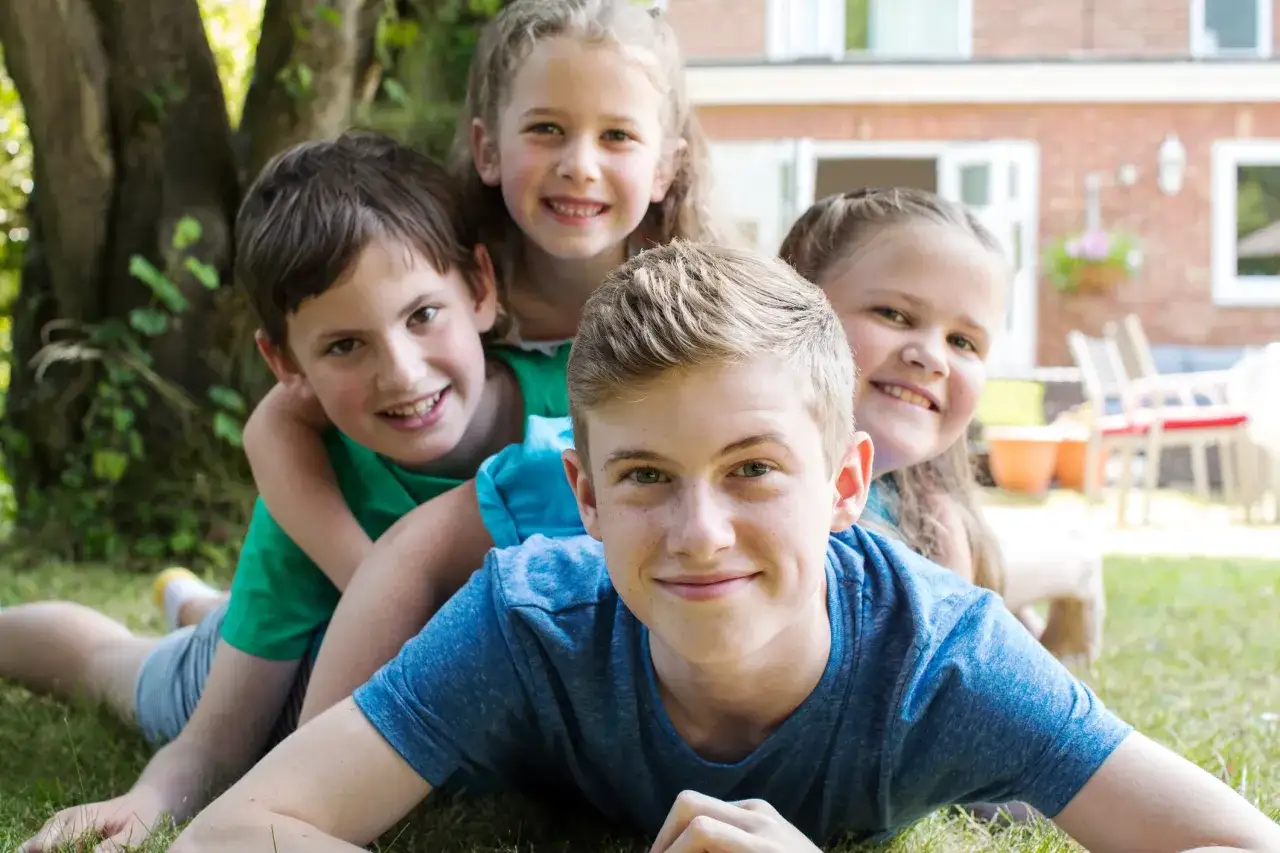 Le sourire de l'ainé de la famille, entouré de ses frères et sœurs, rayonne de joie dans le jardin.