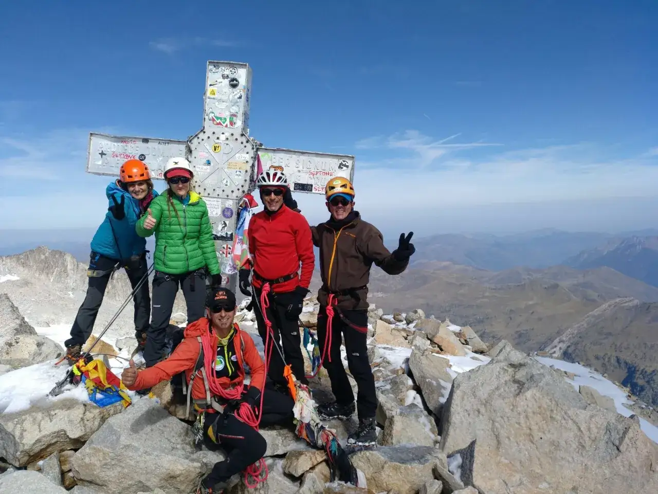 Cinco monta&ntilde;eros celebran en la cima del pico m&aacute;s alto de los Pirineos, junto a una gran cruz met&aacute;lica.