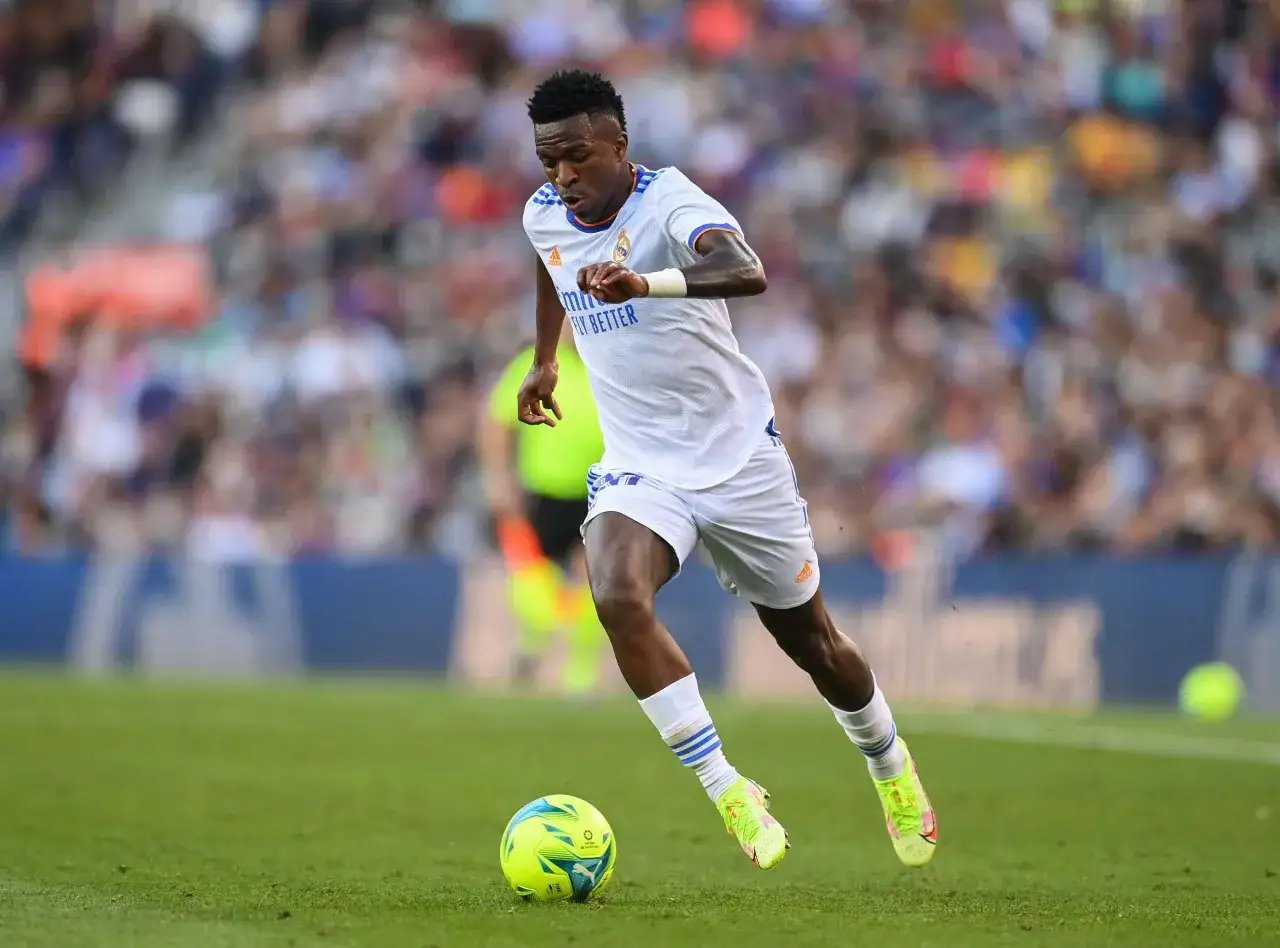 Vinícius Júnior dribbelt im weißen Trikot über den Rasen, der Ball am Fuß.