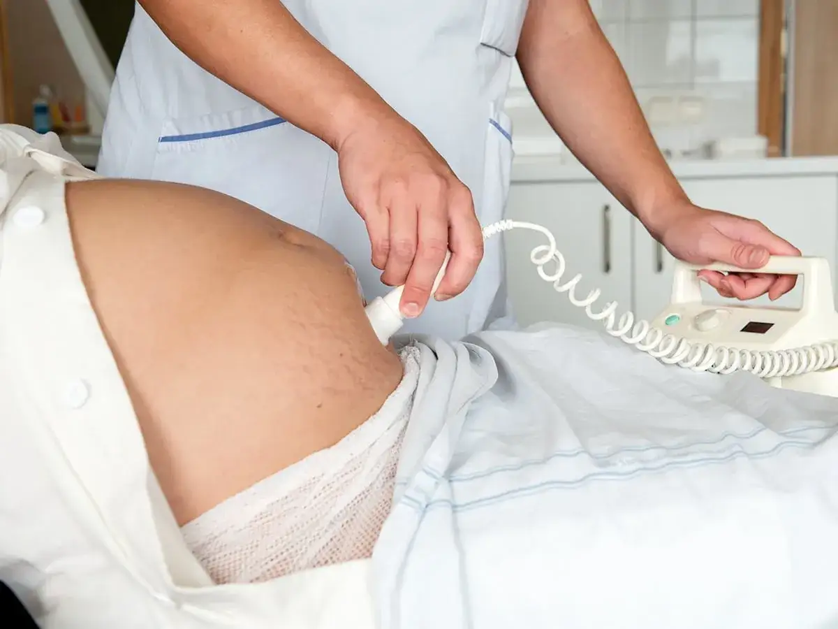 En barnmorska utf&ouml;r en ultraljudsunders&ouml;kning p&aring; en gravid mage, en del av specialistm&ouml;drav&aring;rd.