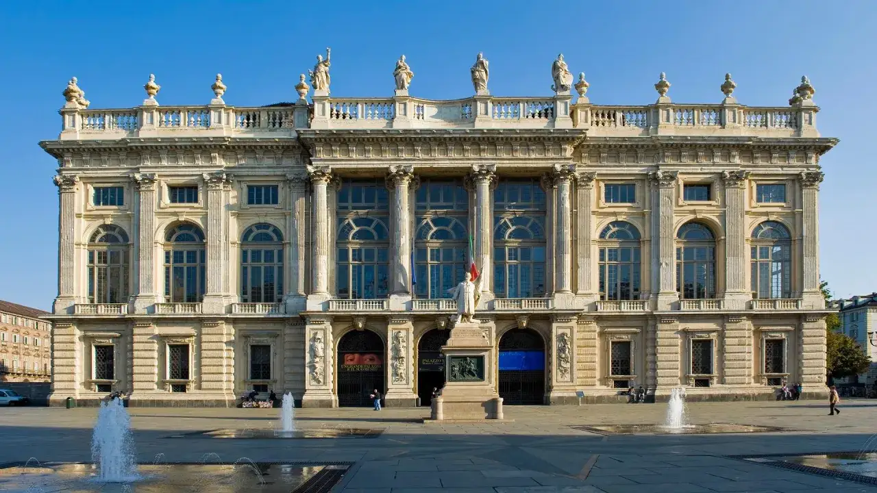 Imponente facciata di Palazzo Madama a Torino, con statue, colonne e fontane che zampillano nella piazza antistante.