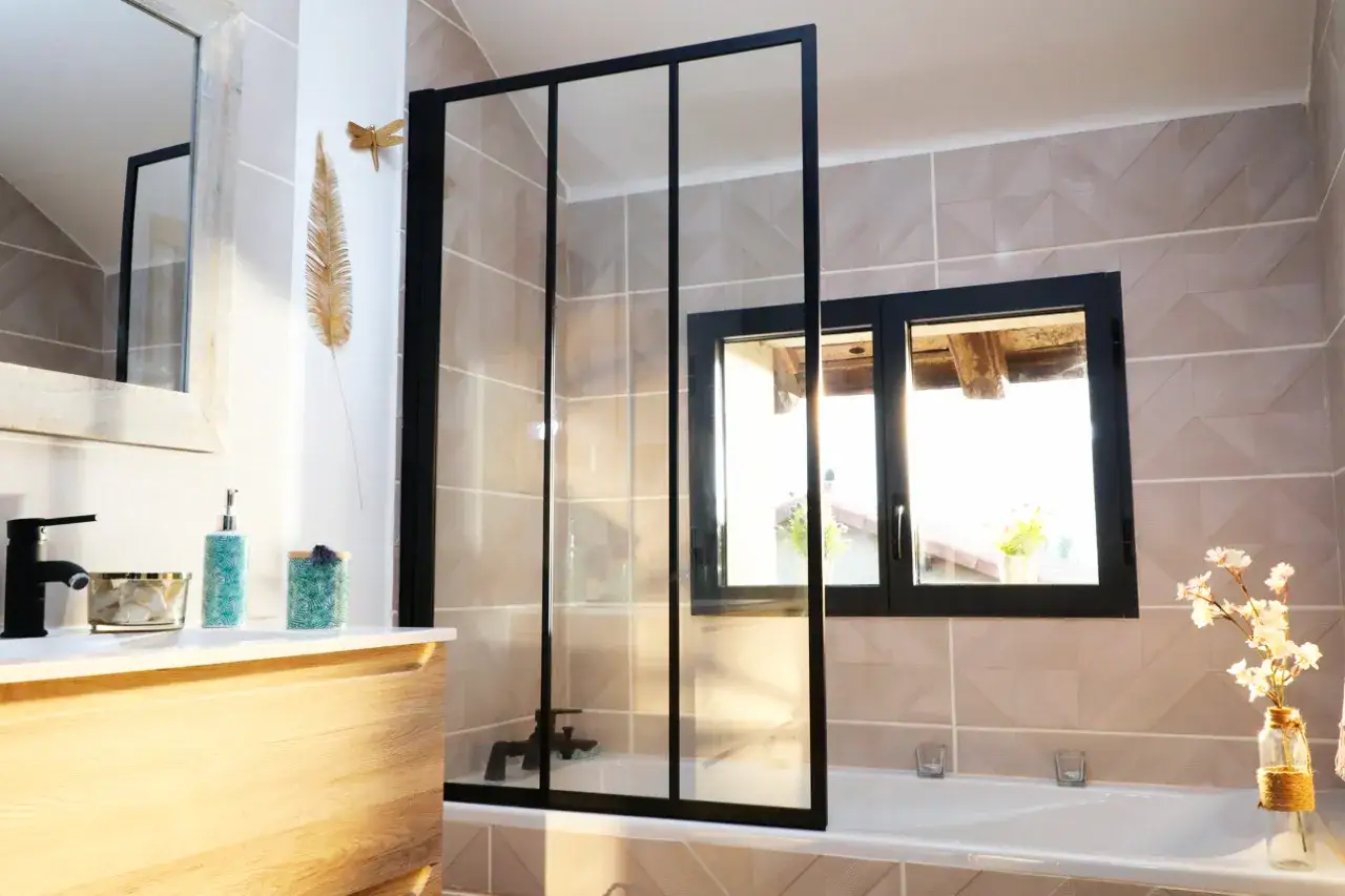Une salle de bain moderne avec une paroi de douche noire, un lavabo en bois et une baignoire.