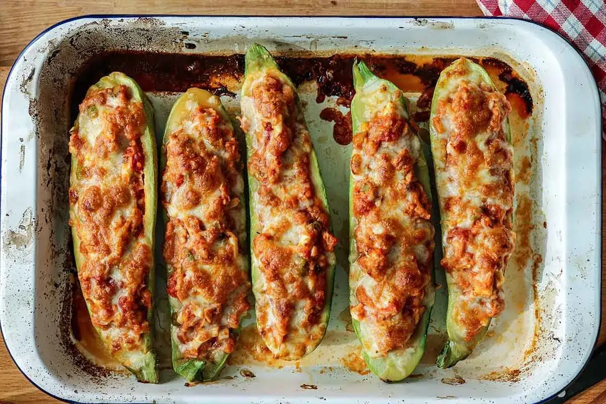 Calabacines rellenos de carne, gratinados con queso, listos para disfrutar en una bandeja de horno.
