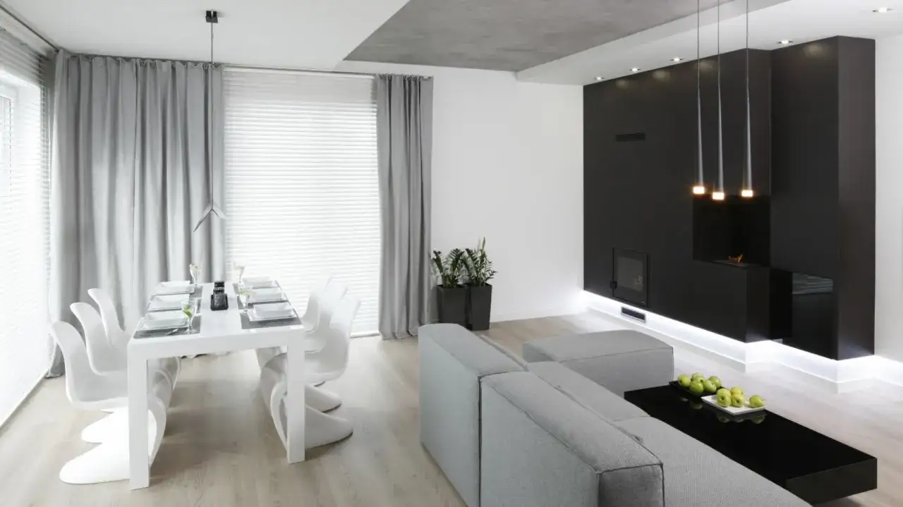 Nowoczesny salon z jadalnią, gdzie centralne miejsce zajmuje elegancki biokominek w salonie, otoczony minimalistycznymi meblami.