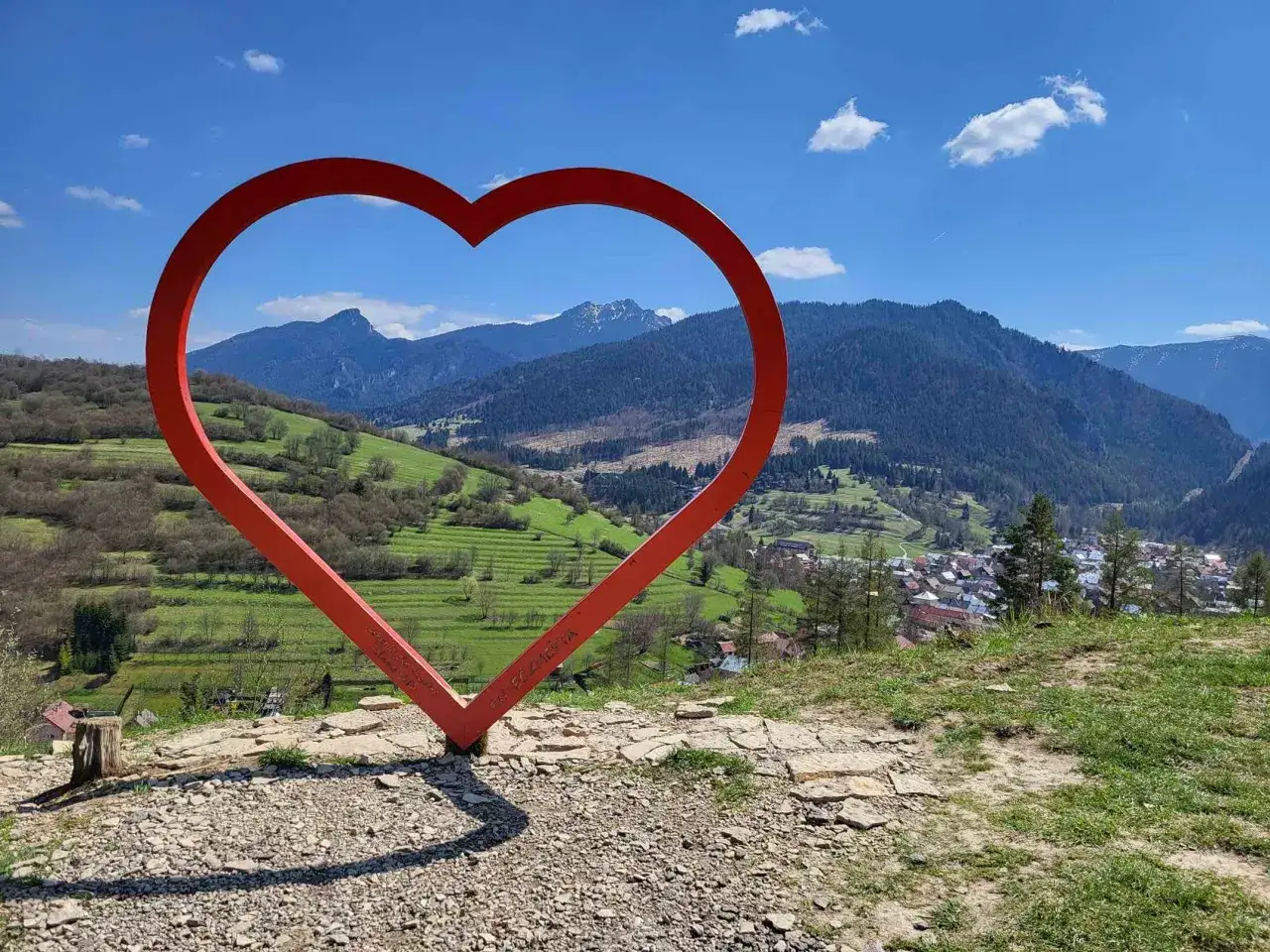 Czerwone serce na tle górskiej panoramy Słowacji. Widok z wieży widokowej na malowniczą dolinę i miasteczko.