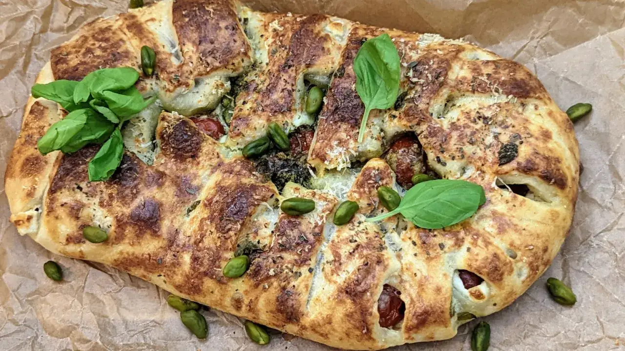 Goldbrauner, gefüllter Stromboli mit Pistazien, Kirschtomaten und Basilikum. Perfekt zum Stromboli essen!