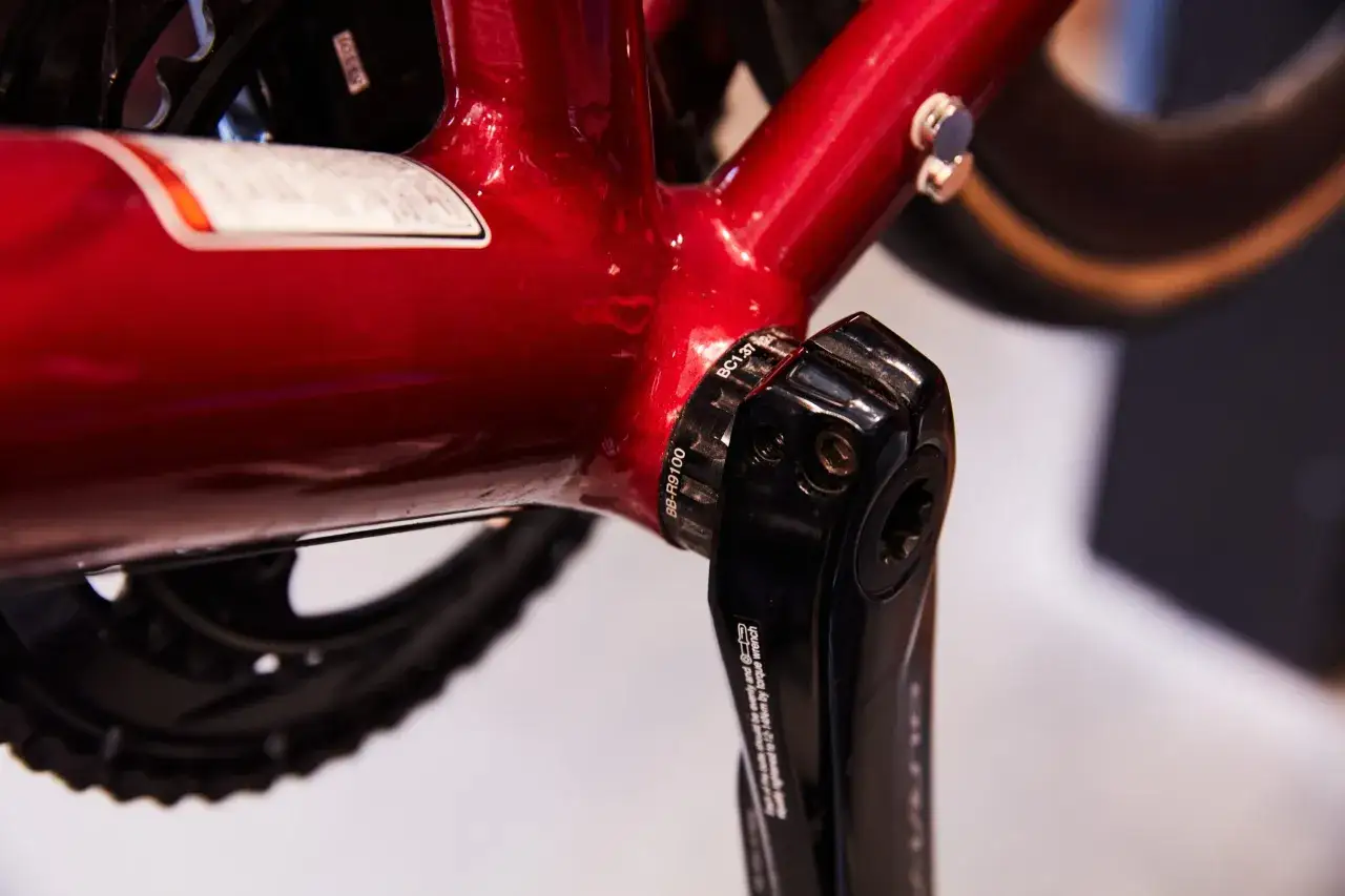 Czerwona rama roweru z widocznym mechanizmem korbowym. Może to być znak, że skrzypiące pedały w rowerze wymagają smarowania.