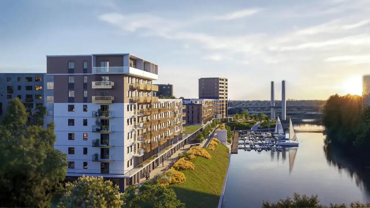 Nowoczesne apartamentowce nad rzeką z mariną. Czy warto inwestować w mieszkania w takiej lokalizacji? Słońce zachodzi nad miastem.