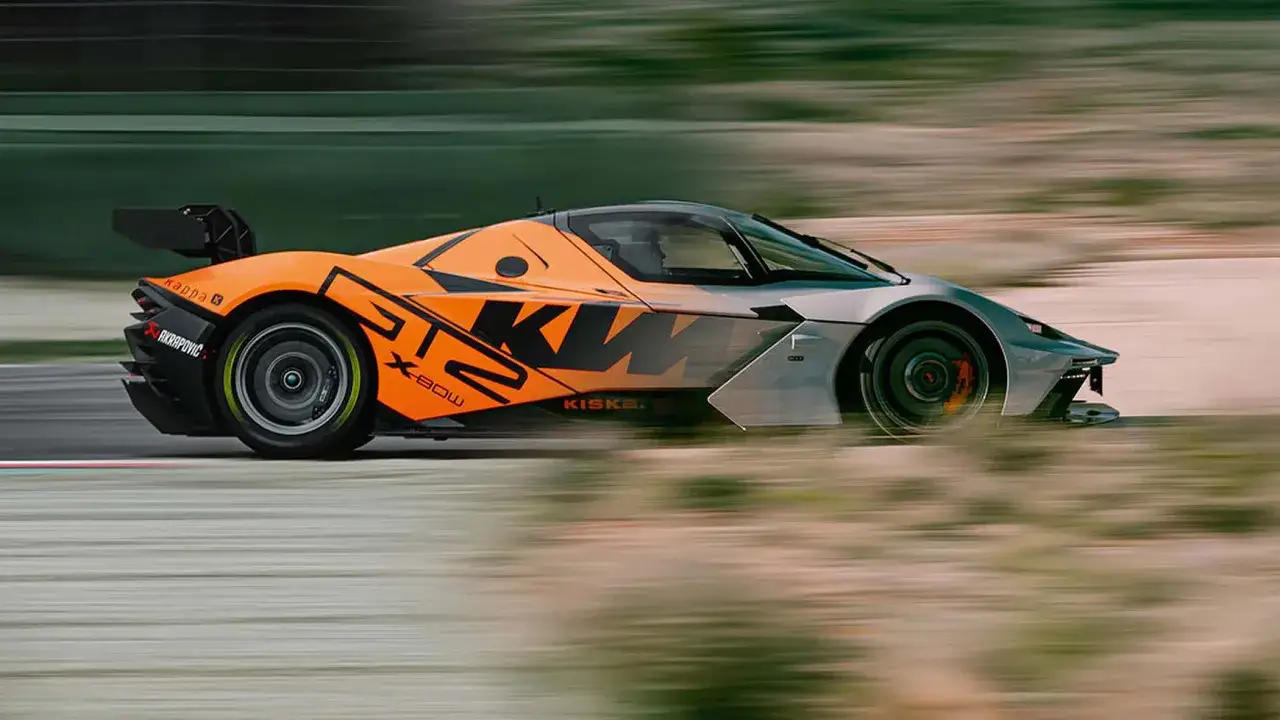 Der orange-silberne KTM GT2 X-Bow rast über die Rennstrecke, die Räder verschwimmen vor Geschwindigkeit.