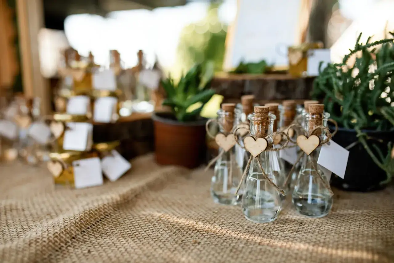Pequeñas botellas de vidrio con corcho, decoradas con corazones de madera y etiquetas blancas, perfectas como detalles comunión.