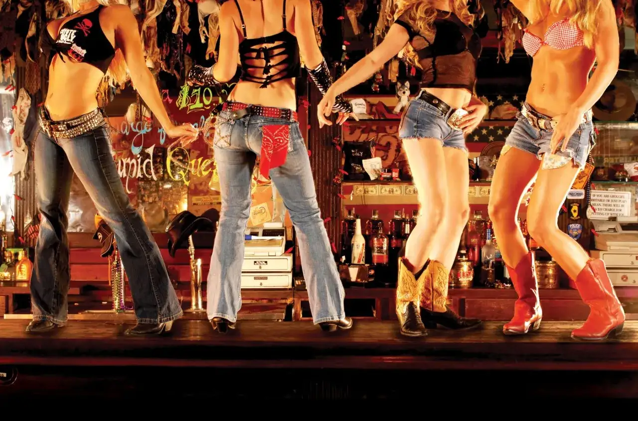 Fyra kvinnor i cowboy-inspirerade kl&auml;der dansar p&aring; en bardisk. Rollistan i Coyote Ugly levererar en energisk show.