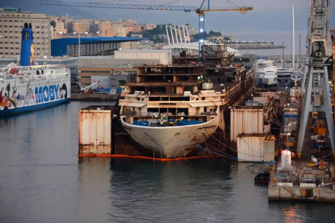 Le Costa Concordia, en d&eacute;molition, est amarr&eacute; dans une cale s&egrave;che, entour&eacute; d'autres navires et de grues.