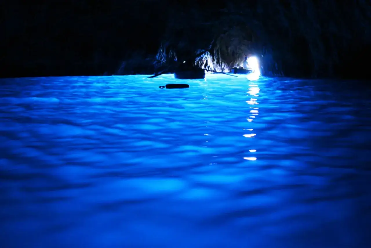 L'acqua della Blaue Grotte brilla di un blu intenso, illuminando una piccola barca all'interno della grotta.