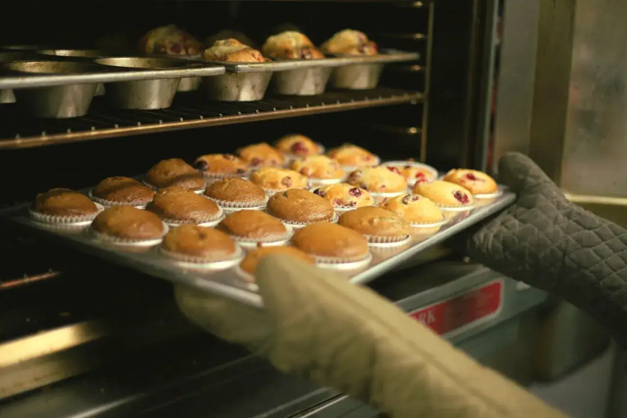Właśnie wyciągam z piekarnika blachę z muffinkami. Zastanawiasz się, jak długo piec muffinki? Te wyglądają na gotowe!