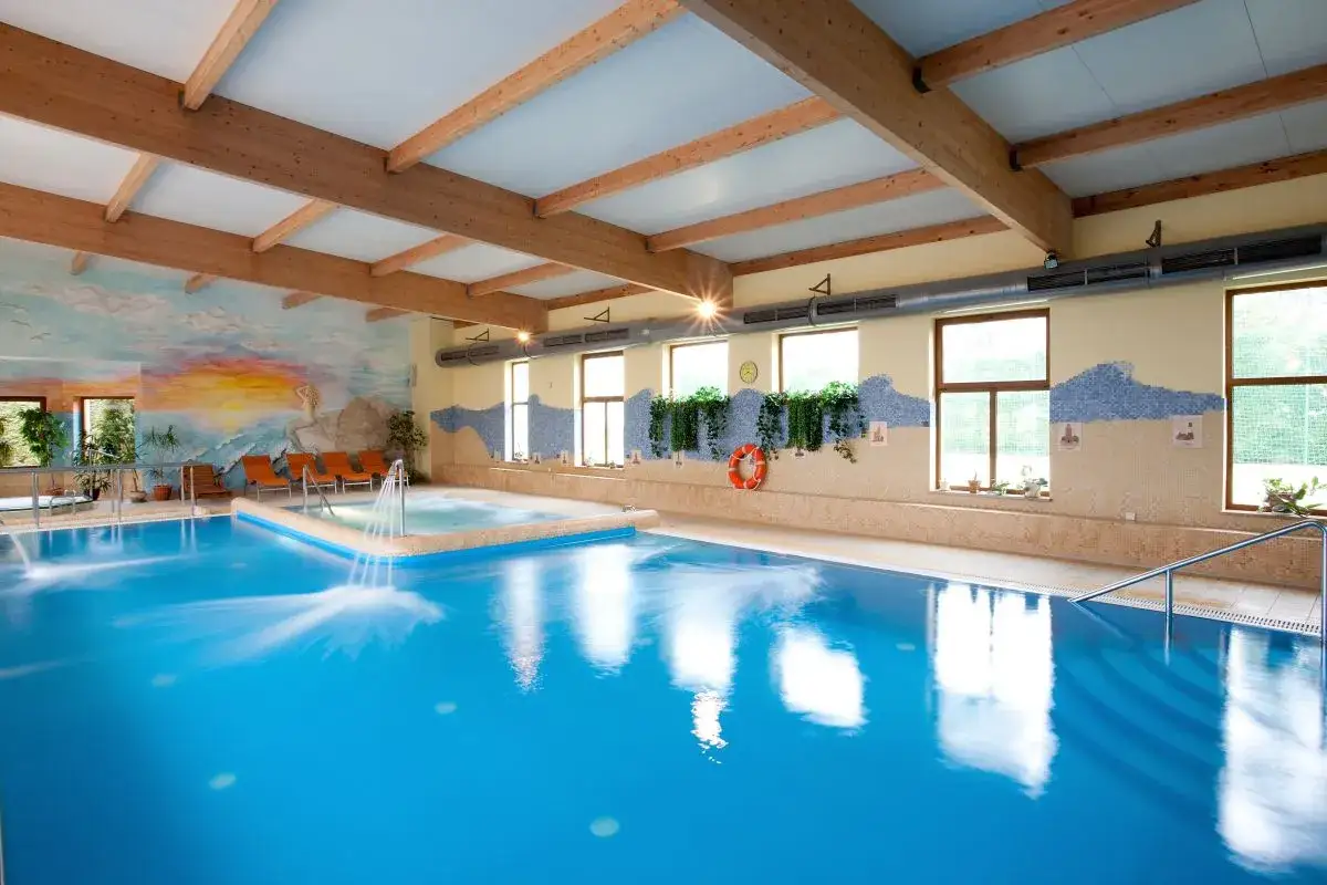 Wodne atrakcje w kompleksie wypoczynkowo rehabilitacyjnym Jantar Spa: basen z hydromasażem i kaskadami, relaks przy muralu.