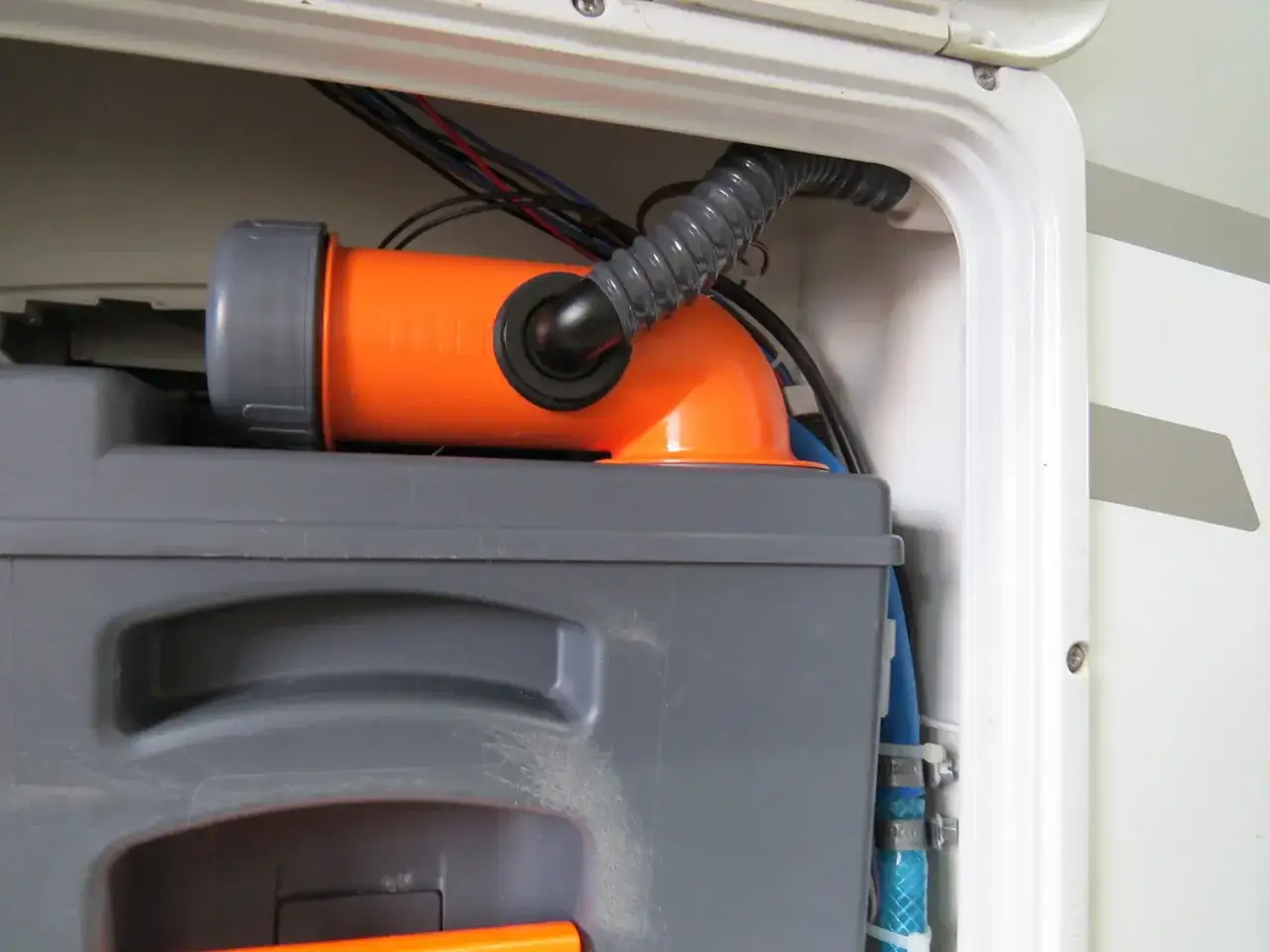 Detaljer från en SOG toalett i en husbil. Orange röranslutning och grå tank.