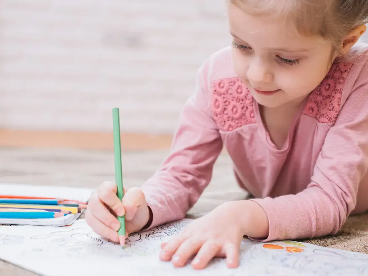 Niña concentrada coloreando, un ejercicio divertido para mejorar caligrafía niños.