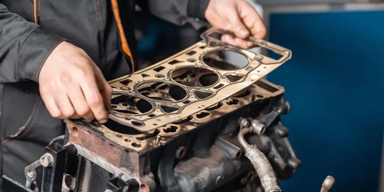 Meccanico posiziona una nuova guarnizione della testata su un motore. Scopri quanto costa cambiare la guarnizione della testata.