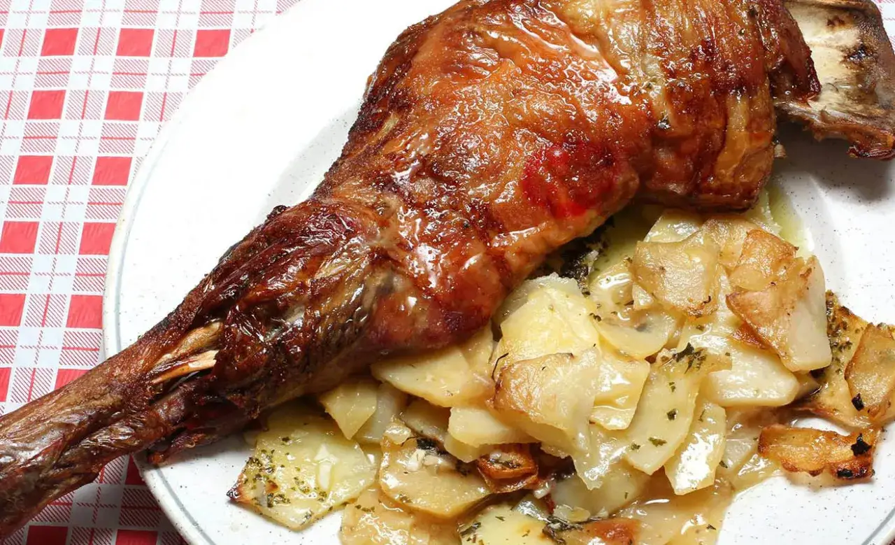 Delicioso ternasco al horno, jugoso y dorado, servido con patatas panadera.
