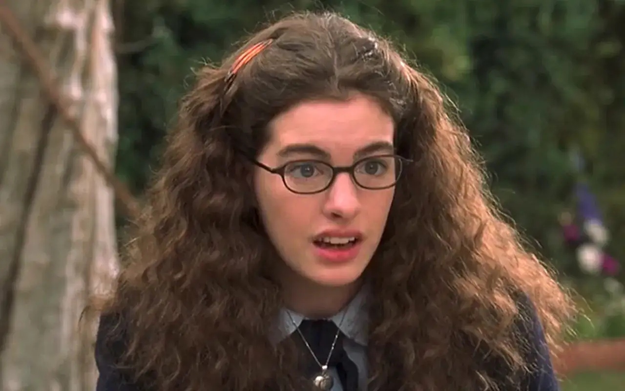 En ung kvinna med glasögon och stort, lockigt hår, som påminner om Mia Thermopolis från