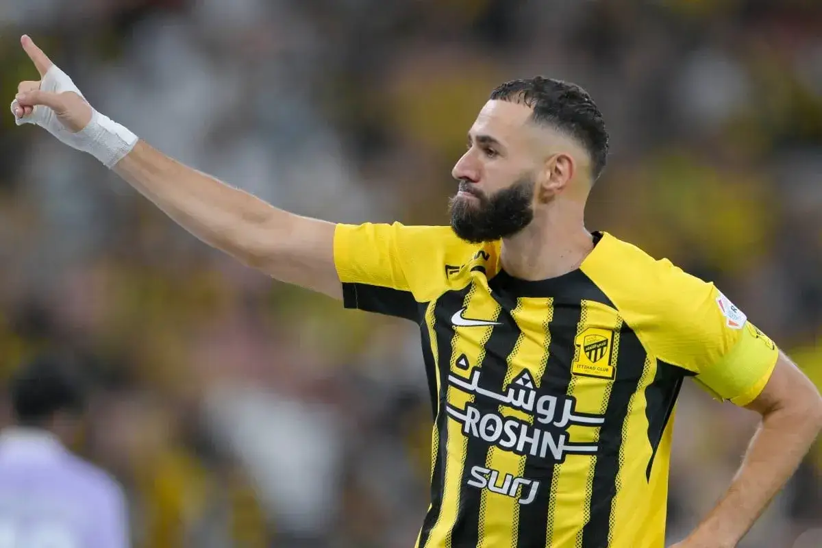 Karim Benzema w żółto-czarnej koszulce, z ręką uniesioną w geście zwycięstwa. Właśnie tam gra Benzema.