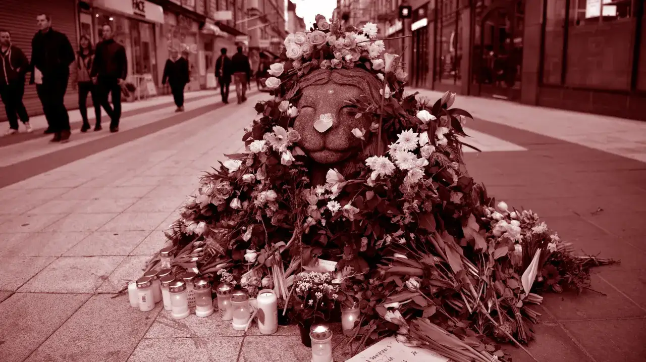 Minnesplats med blommor och ljus efter terrord&aring;det p&aring; Drottninggatan. En stenlejon pryds av blomsterkrans.