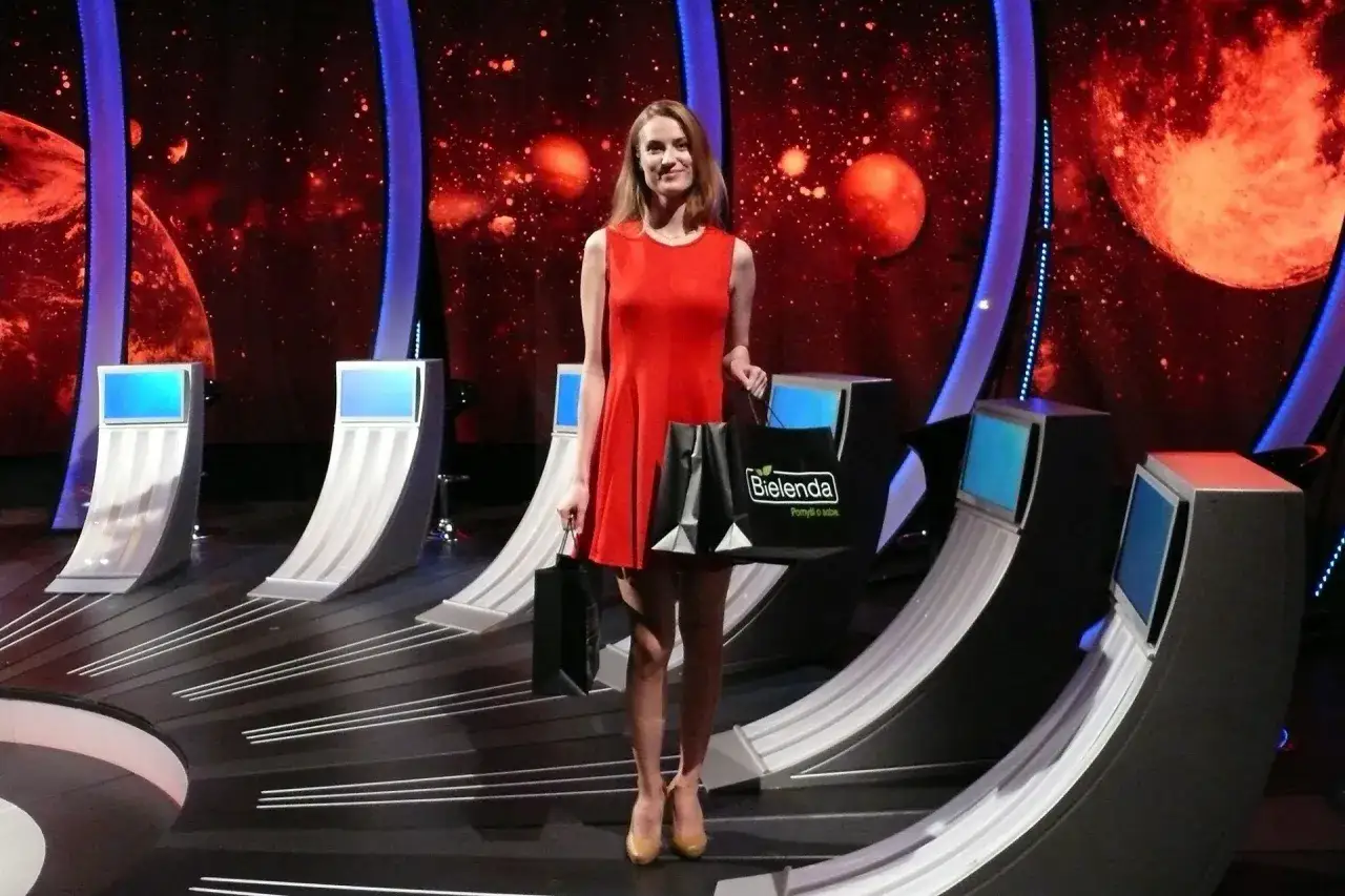 Sylwia Toczyńska w czerwonej sukience, z torbami Bielenda, na tle kosmicznej scenografii.