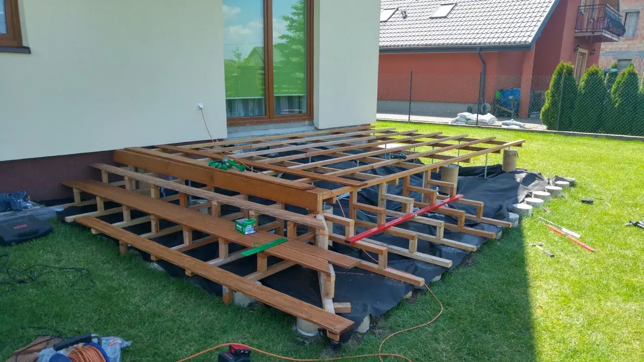 Budowa tarasu na słupach betonowych. Drewniana konstrukcja czeka na deski.