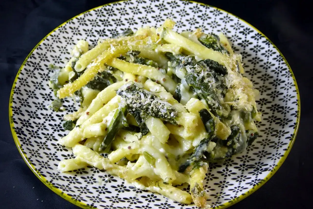 Caciocavallo-Alternative: cremige Pasta mit Spinat und geriebenem Käse auf einem gemusterten Teller.